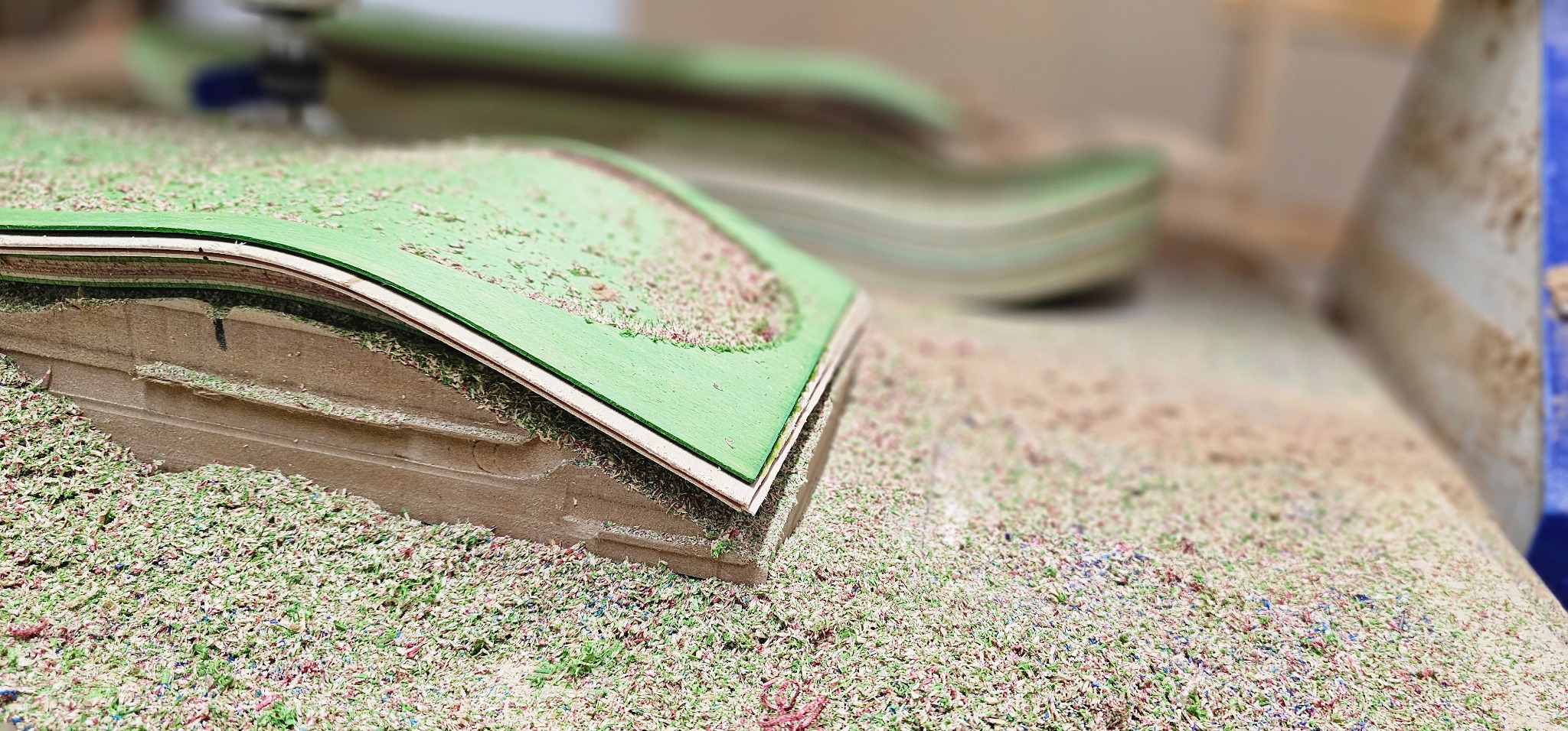 Close-up of skateboard profile trimming on a custom CNC fixture