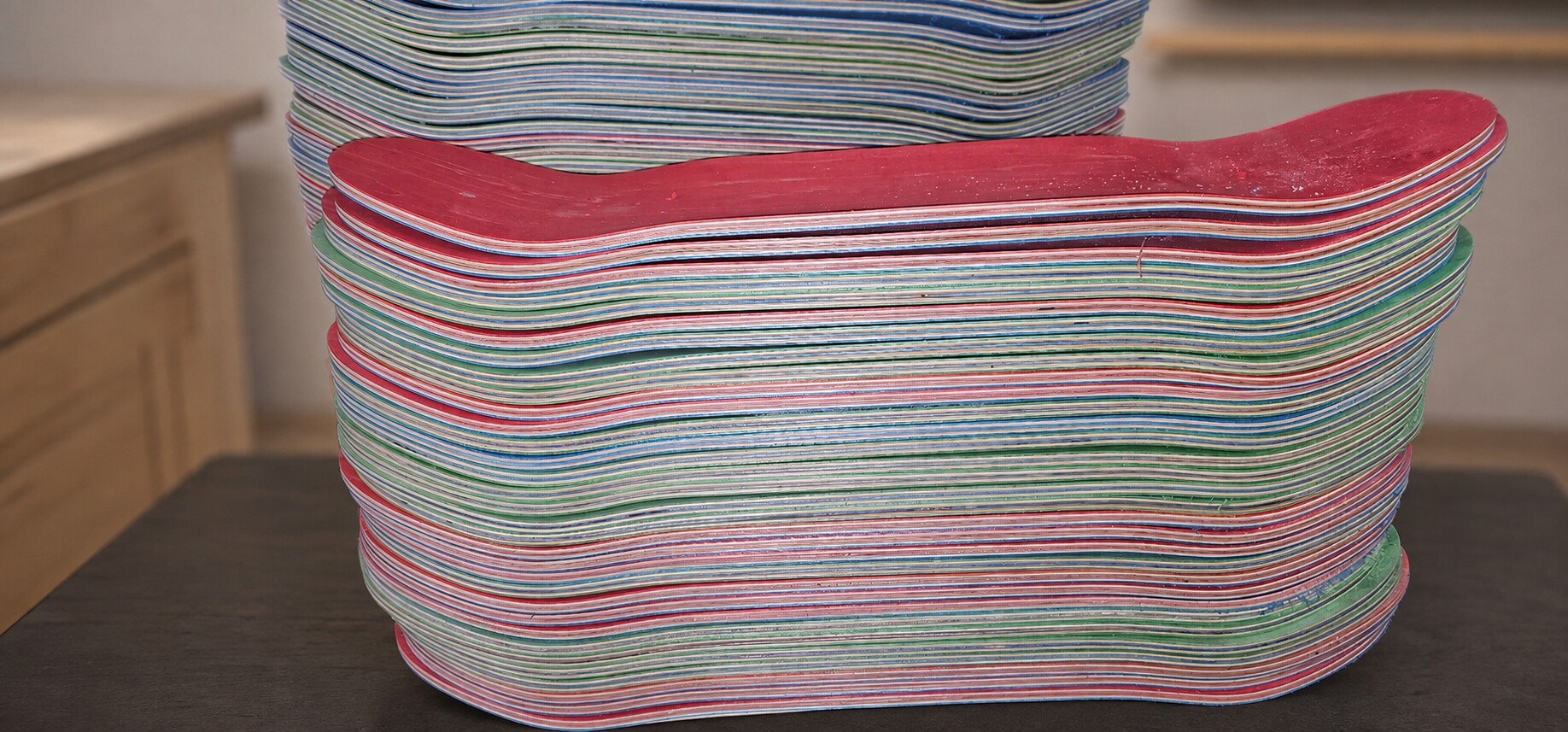 Large stack of pressed skateboard decks shown at its natural panoramic scale against a clean shop background